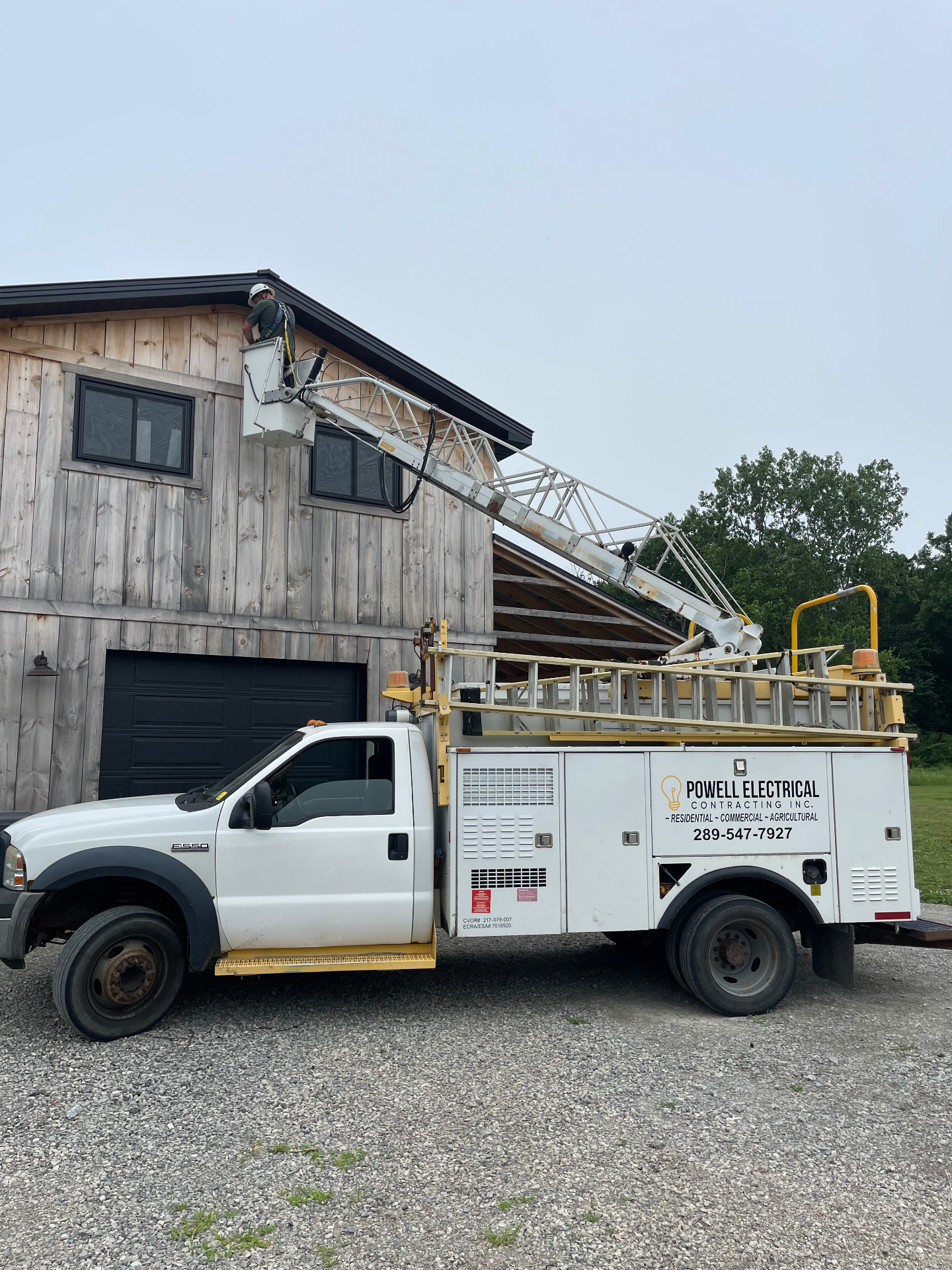 Powell Electrical bucket truck with boom extended, servicing a two-story building